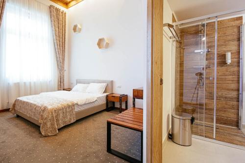 a bedroom with a bed and a glass shower at Buchenland Hotel in Câmpulung Moldovenesc