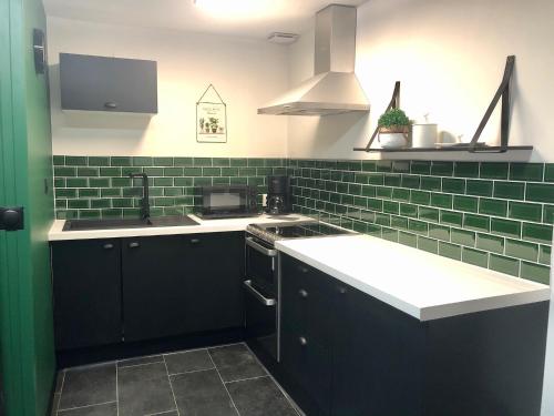 eine Küche mit schwarzen Schränken und grünen U-Bahn-Fliesen in der Unterkunft Le charme et l’original in Ailly-le-Haut-Clocher