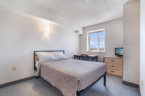 a bedroom with a bed and a television in it at Residence & Conference Centre - Welland in Welland