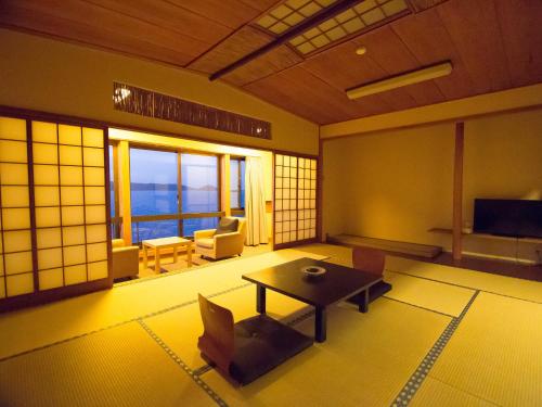 a living room with a table and chairs and a television at Wakayama Kada Onsen Kada Kaigetsu (ex. Azumaya Seaside Hotel) in Wakayama