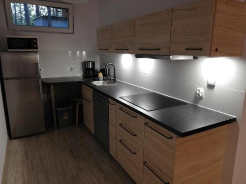 a kitchen with wooden cabinets and a black counter top at Domek nad jeziorem 7 in Kamienica Królewska