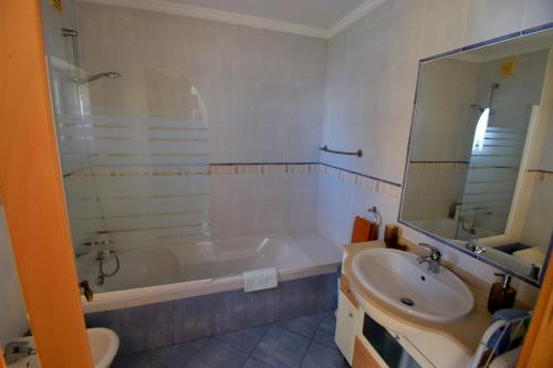 a bathroom with a tub and a sink at Piscina Apartment in Santa Luzia