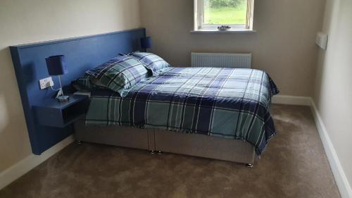 a bedroom with a bed with a blue head board at Bridgeburn Apartment in Letterkenny