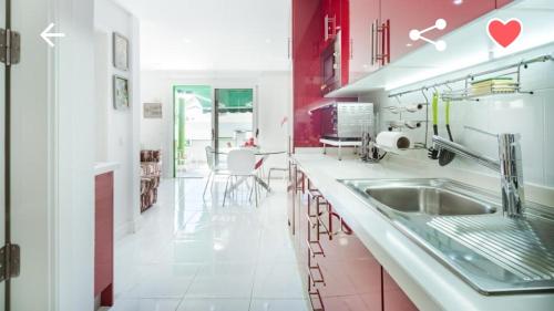 una cocina con armarios rojos y blancos y fregadero en Bungalow con piscina Maspalomas, en Maspalomas