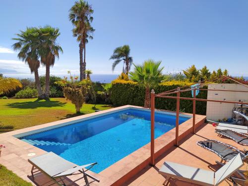 una piscina con sillas y el océano en el fondo en Villa Carioca - with private pool, marvelous garden and amazing ocean view en Sauzal