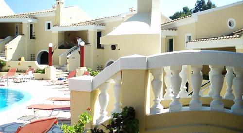 a white railing next to a house with a swimming pool at Mediterranean Blue in Kavos
