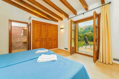 een slaapkamer met een blauw bed en een balkon bij Villa Vall den March in Pollença