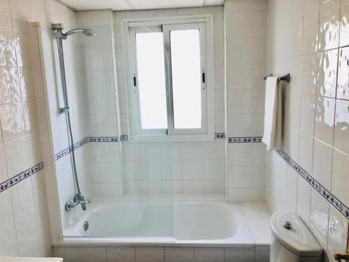 a white bathroom with a tub and a window at Charming apartment with a stunning sea view in Málaga