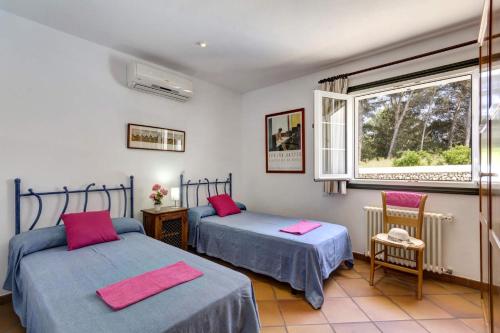 two beds in a room with a window at Ca'n toni Villa, Cala Galdana in Ferreries
