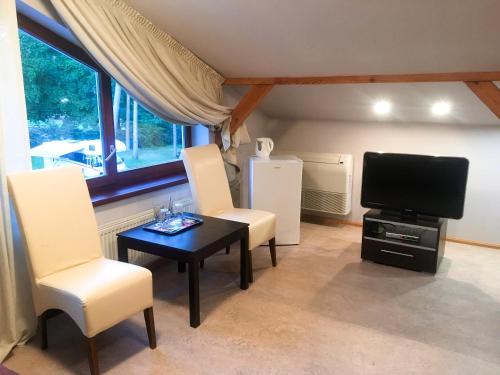 a living room with a television and a table and chairs at Valensija in Jūrmala