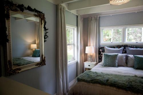 タウランガにあるSunny Brae Cottagesのベッドルーム(大きな鏡、ベッド付)
