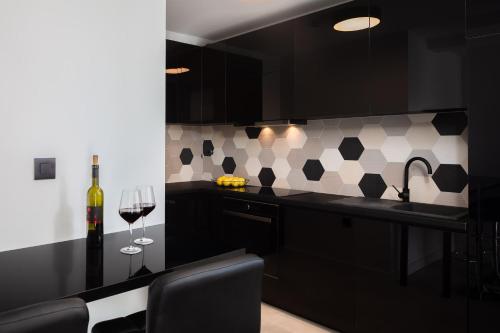 a kitchen with black cabinets and two glasses of wine at Villa 9 in Podstrana