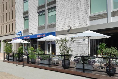 a restaurant with tables and umbrellas in front of a building at Vignette Collection Yours Truly DC, an IHG Hotel in Washington, D.C.