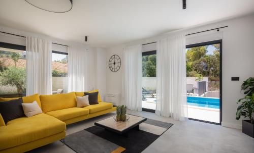 a living room with a yellow couch and windows at Villa 9 in Podstrana