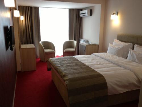 um quarto de hotel com uma cama e cadeiras e uma janela em CITY HOTEL & LOUNGE em Slatina