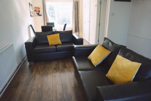 a living room with two black couches and yellow pillows at The Harvest 2 in Canterbury