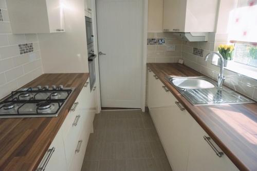 a white kitchen with a sink and a stove at The Harvest 2 in Canterbury