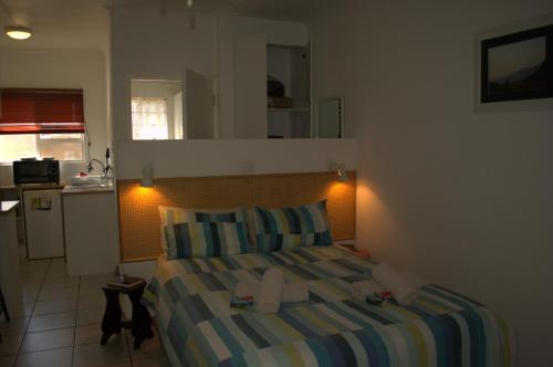 a small bedroom with a bed and a kitchen at Crowned Crane in Gonubie