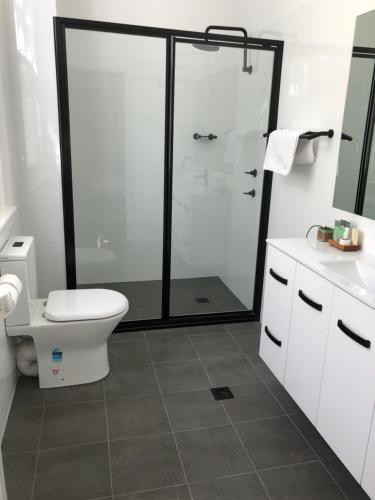 a bathroom with a toilet and a glass shower at Vine Valley Inn in Cessnock