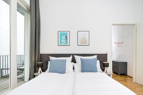 um quarto com uma grande cama branca com almofadas azuis em BENSIMON apartments Prenzlauer Berg em Berlim