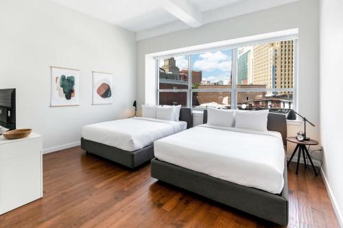 Duas camas num quarto com uma janela grande em Kislak 402 Spacious 1BR Retreat Above the City em Newark