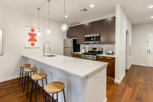 uma cozinha com um grande balcão branco e bancos em Kislak 405 Luxurious 1BR Retreat Above the City em Newark