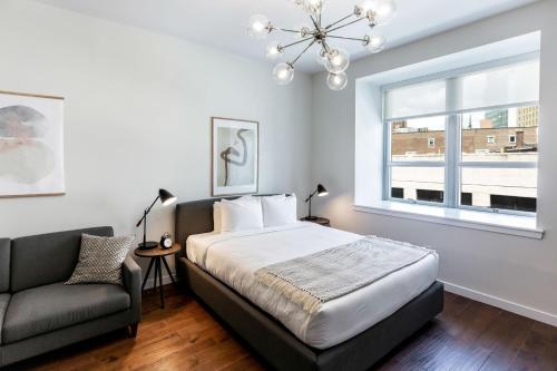 a bedroom with a bed and a couch and a window at Kislak 304 Chic Studio in the Heart of Downtown in Newark