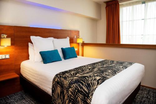 a hotel room with a large bed with blue pillows at Best Western Plus Hôtel Colbert in Châteauroux