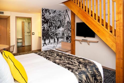 a bedroom with a bed and a tv on a wall at Best Western Plus Hôtel Colbert in Châteauroux