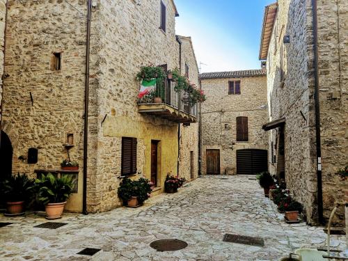 an alley in an old stone building with a balcony at Casa vacanze Acero rosso in Massa Martana