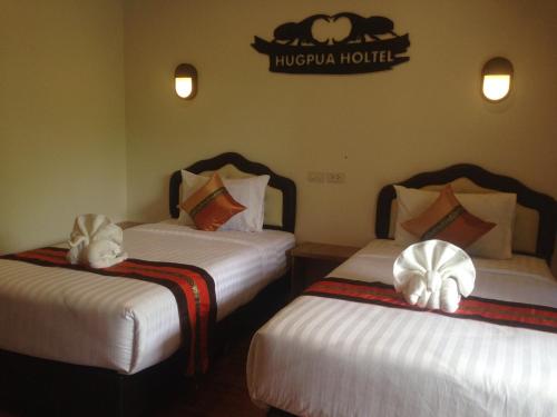 a hotel room with two beds with white sheets at Hugpua Hotel in Nan