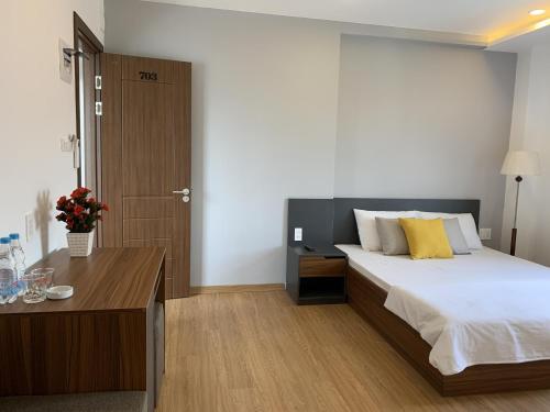 a bedroom with a large bed and a wooden table at Rang Dong Hue Hotel in Hue