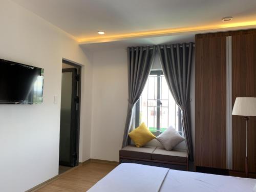 a bedroom with a bed and a window with a couch at Rang Dong Hue Hotel in Hue
