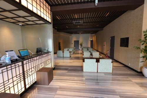 a lobby with a long hallway with desks and chairs at Hotel Kanade Kanku Kaizuka in Kaizuka
