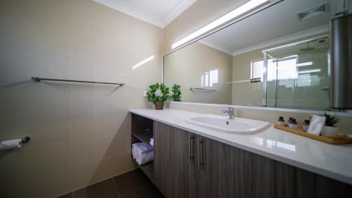 a bathroom with a sink and a mirror at Hamilton's Queanbeyan Motel in Queanbeyan