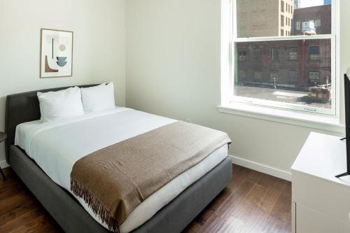 a white bedroom with a bed and a window at Kislak 303 Luxurious 2BR in Heart of Downtown in Newark
