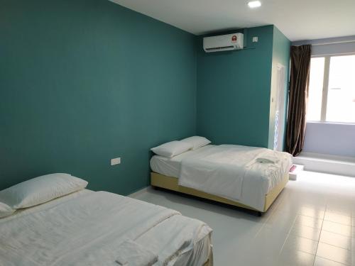 a bedroom with two beds and a blue wall at Qeyjan Hotel in Pasir Puteh