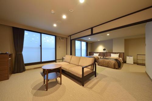 美瑛町にある湯元　白金温泉　ホテルのベッド、ソファ、テーブルが備わるホテルルームです。