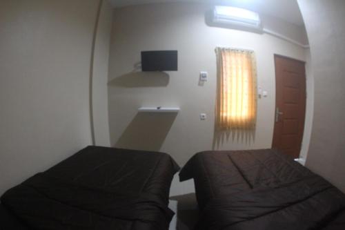 a small room with two beds and a window at Garuda Kostel in Tegal