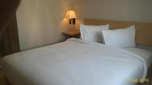 uma grande cama branca num quarto de hotel em Omnea Hotel - Syariah em Bengkulu