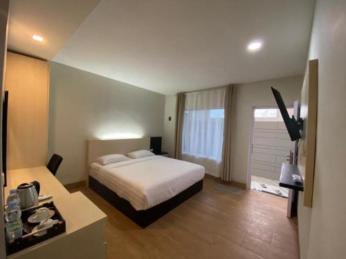 a hotel room with a bed and a television at Wisma Lovebird in Kalianget