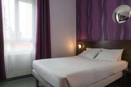 a bedroom with a large white bed with purple curtains at Urban Style, Hôtel Le Cheval Noir, Saint-Étienne in Saint-Étienne