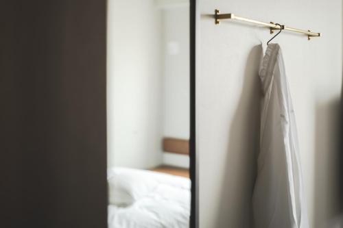 a robe hanging on a wall next to a bed at Nest Hotel Hiroshima Ekimae in Hiroshima