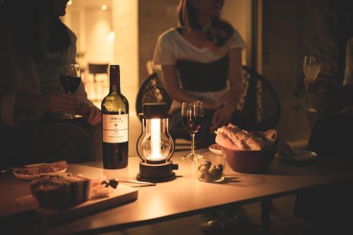 a woman standing next to a table with a bottle of wine at Nest Hotel Hiroshima Ekimae in Hiroshima