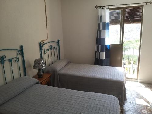 sypialnia z 2 łóżkami i oknem w obiekcie PENSION LA FUENTE w mieście Abrucena