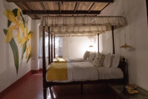 een slaapkamer met een hemelbed met witte lakens en kussens bij Bate Papo House Cafe Boutique in Saligao