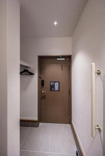a hallway with a door with a sign on it at GRAND BASE Okayama Ekimae in Okayama