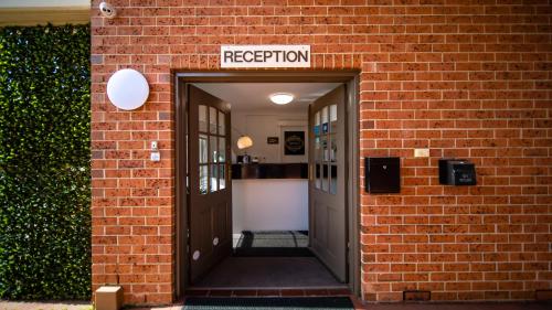 an entrance to a brick building with a sign that reads reception at Hamilton's Queanbeyan Motel in Queanbeyan