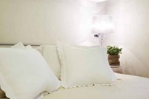 a white bed with white pillows and a lamp at Petite Suite in Bergamo