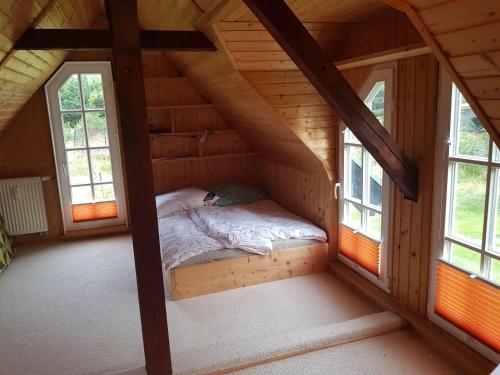 a bed in a log cabin with two windows at Niedliches-kleines-Ferienhaeuschen-auf-Ruegen-nahe-Stralsund in Altefähr